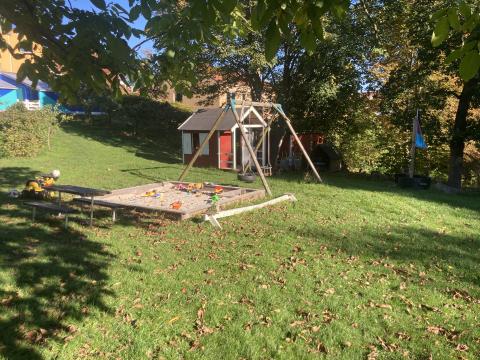 Legeplads med sandkasse, gynger, legehus og lille piratskib.